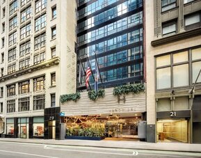 Hotel entrance with signage, greenery, and welcoming street-level access at Hotel Hendricks.