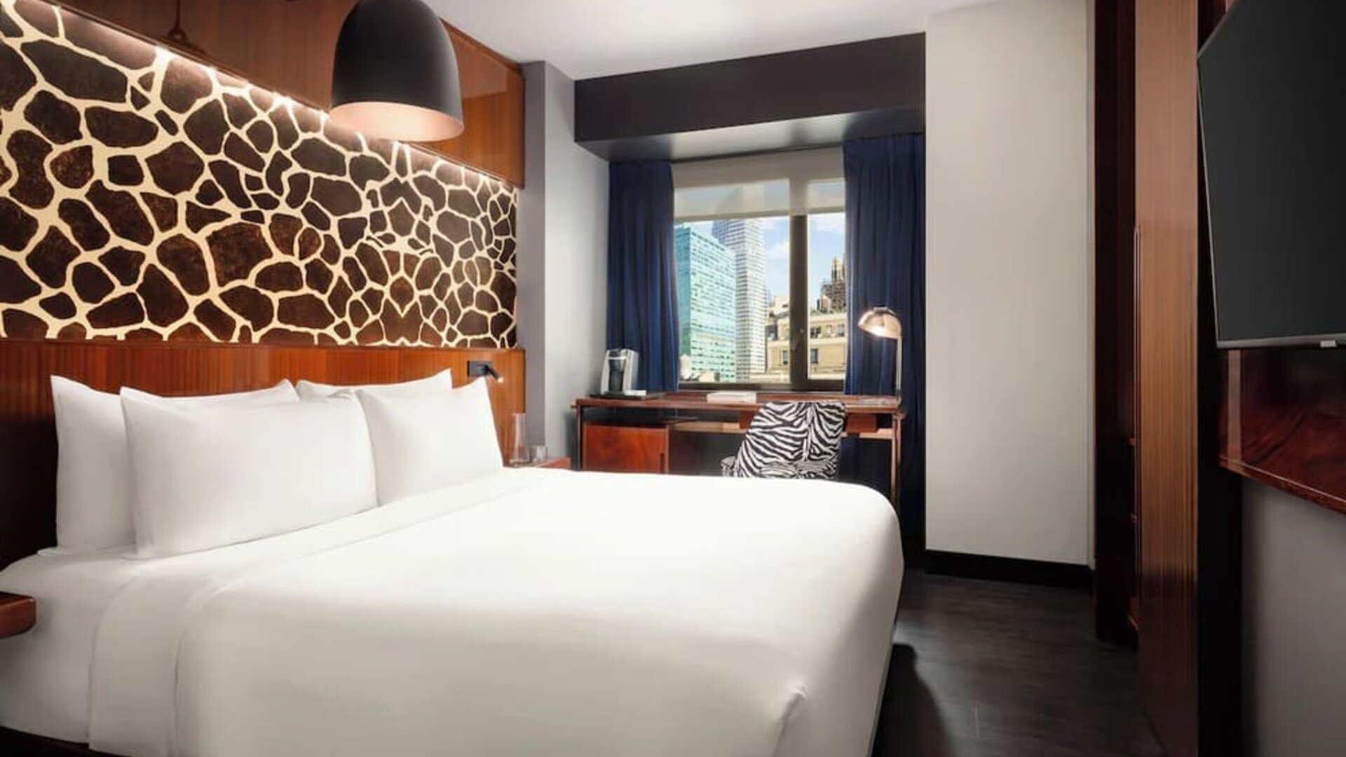 King room with modern décor, wall-mounted TV, workspace, and large window at Hotel Hendricks.