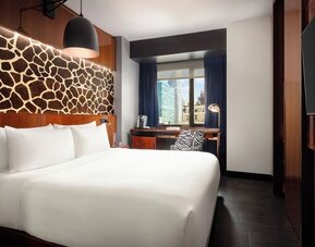 King room with modern décor, wall-mounted TV, workspace, and large window at Hotel Hendricks.