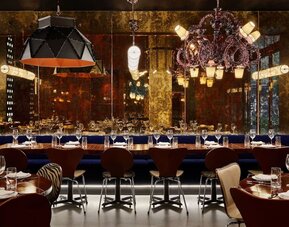 Upscale dining area with ambient lighting, chandeliers, and elegant table settings at Hotel Hendricks.