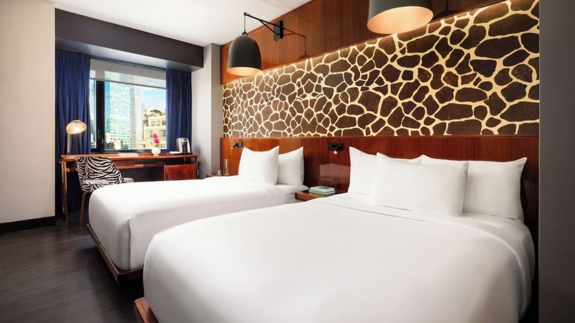 Double room with two beds, feature wall design, and workspace by the window at Hotel Hendricks.