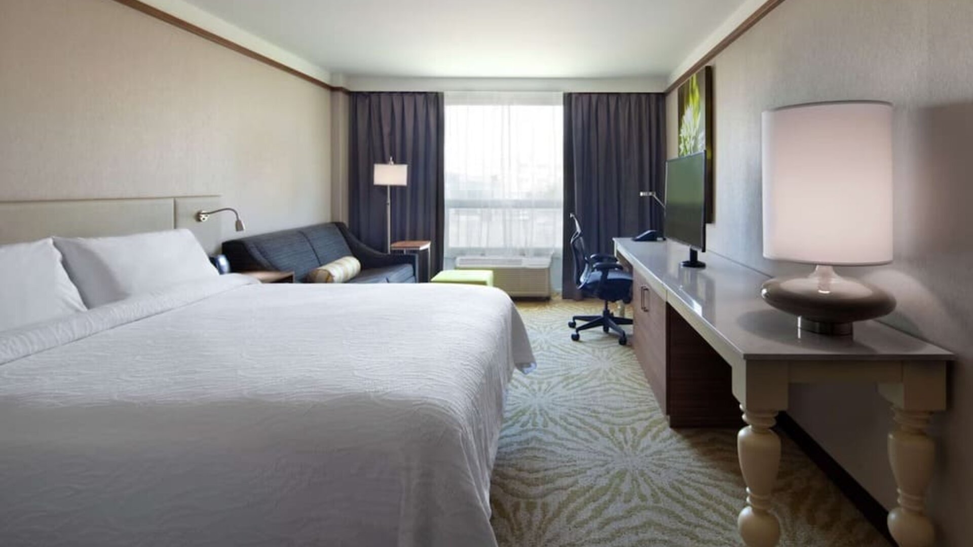 day use room with table, lamp shade, and work station at Hilton Garden Inn Montreal Airport.