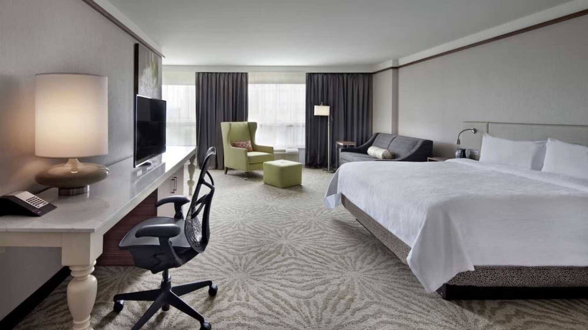 King bedroom with work desk and work chair and TV at Hilton Garden Inn Montreal Airport.