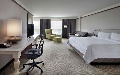 King bedroom with work desk and work chair and TV at Hilton Garden Inn Montreal Airport.