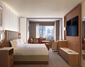 Guest room with extended seating area, sofa, and city views at Hyatt Regency Times Square.