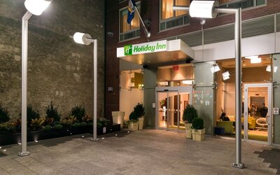 Hotel front entrance with illuminated signage and glass doors at Holiday Inn New York City - Times Square By IHG.