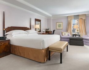 Bedroom with natural light, plush bedding, and comfortable seating at The Michelangelo New York.