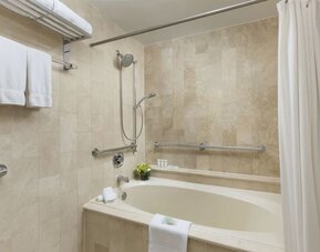 Bathroom with soaking tub, shower combination, and marble tile finishes at The Michelangelo New York.
