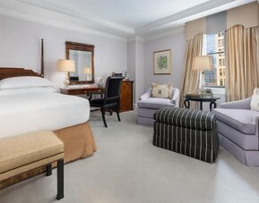 Classic guest room with plush bedding, writing desk, and elegant seating area at The Michelangelo New York.