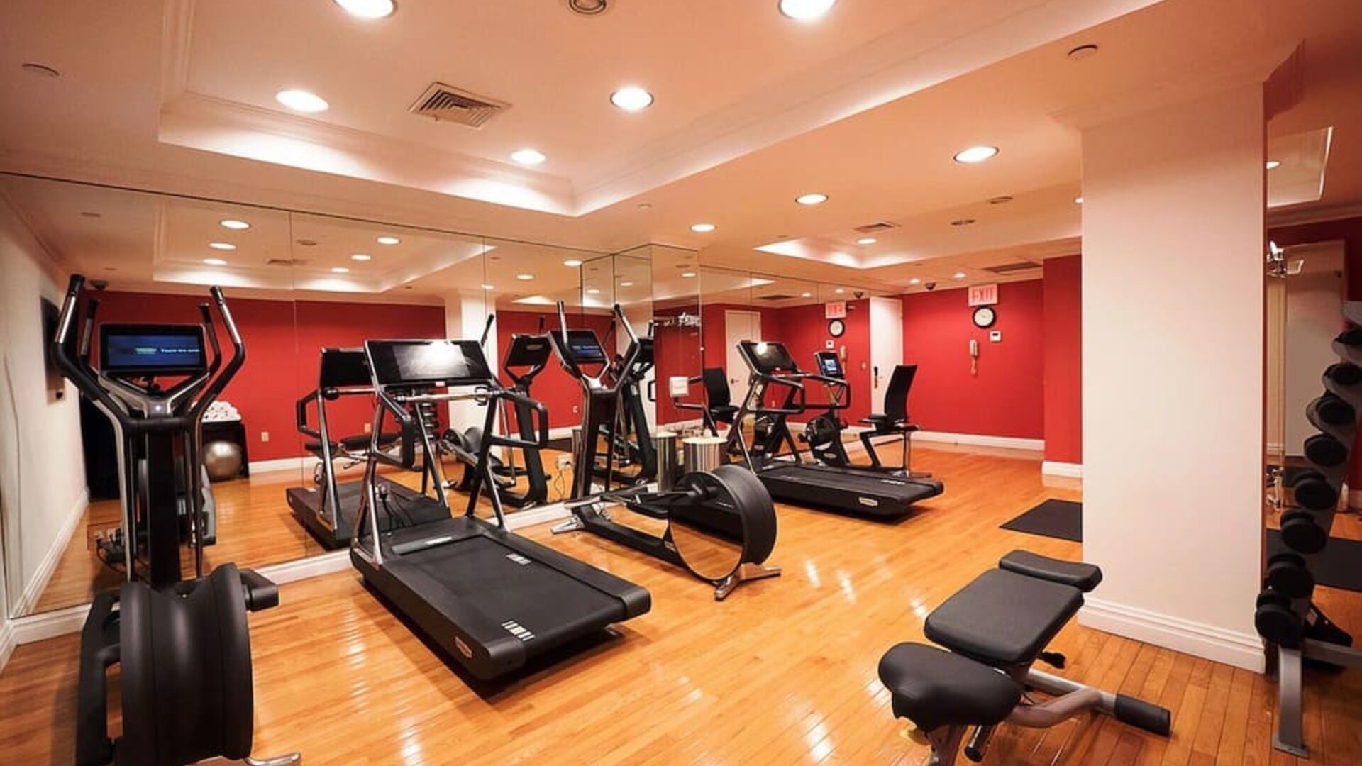 Fitness center with cardio machines, free weights, and mirrored walls at The Michelangelo New York.