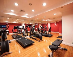 Fitness center with cardio machines, free weights, and mirrored walls at The Michelangelo New York.