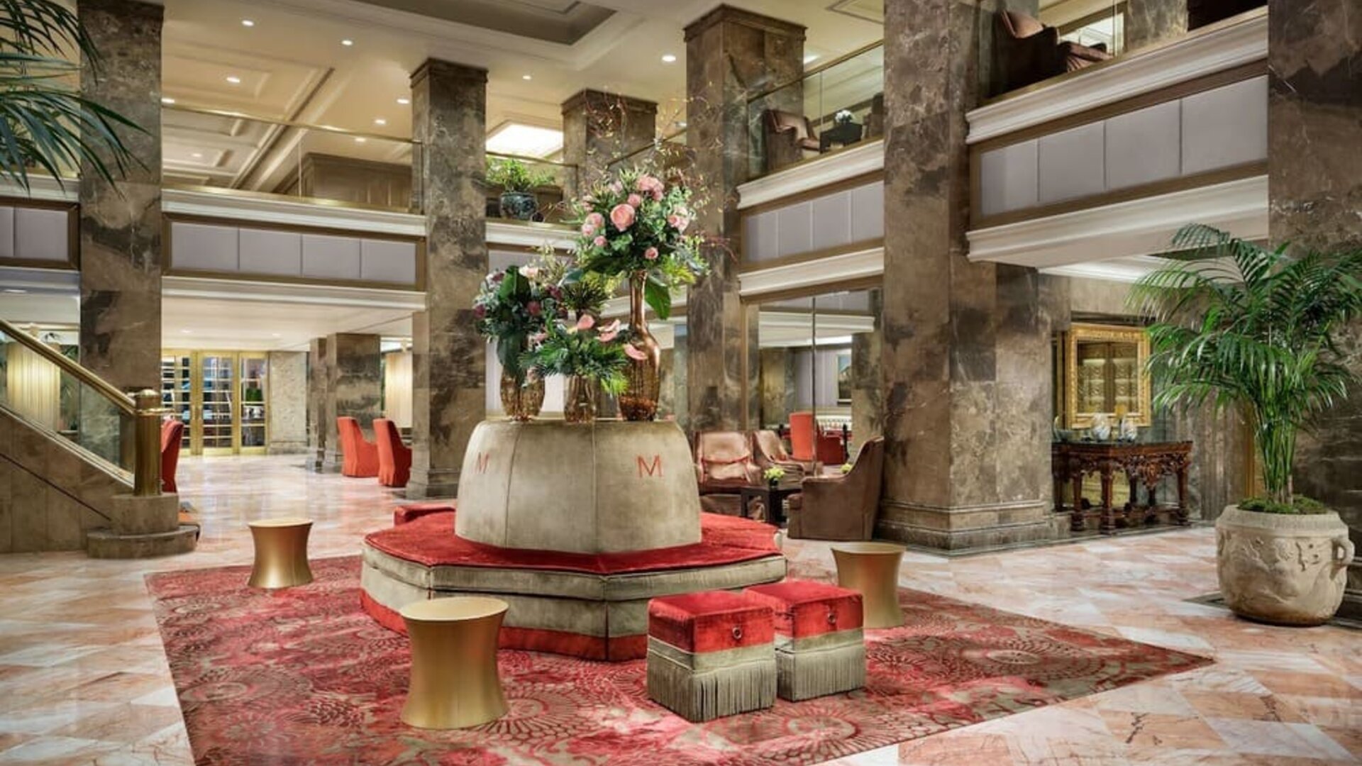 Grand lobby with marble floors, decorative columns, and floral centerpiece at The Michelangelo New York.