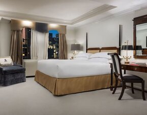 King bedroom with warm tones, desk area, and refined classic styling at The Michelangelo New York.