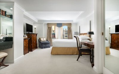 Spacious suite with separate living area, desk workspace, and city views at The Michelangelo New York.