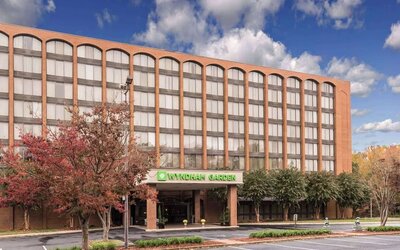 Hotel exterior with Wyndham Garden signage, covered entrance, and parking area at Wyndham Garden Williamsburg Busch Gardens Area.