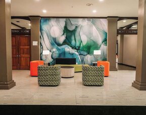 Lobby seating area with modern chairs, decorative wall art, and open layout at Wyndham Garden Williamsburg Busch Gardens Area.