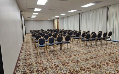 Meeting room with rows of banquet-style chairs, patterned carpet, and bright overhead lighting set up for a conference at Wyndham Garden Williamsburg Busch Gardens Area.