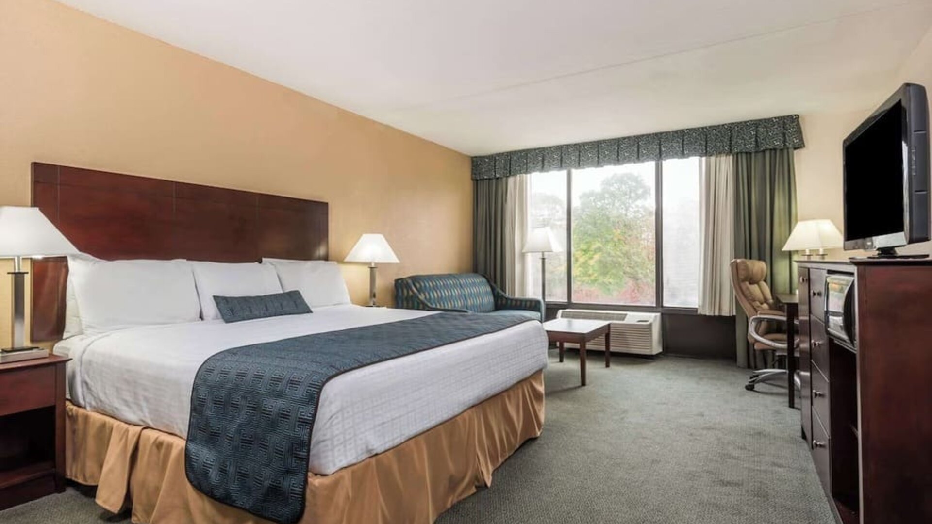 Guest room with natural light, large window, and comfortable seating area at Wyndham Garden Williamsburg Busch Gardens Area.