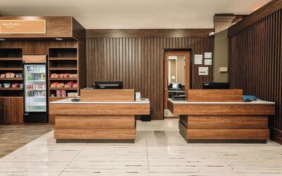Reception desk area with wood finishes, snack station, and front desk service area at Wyndham Garden Williamsburg Busch Gardens Area.
