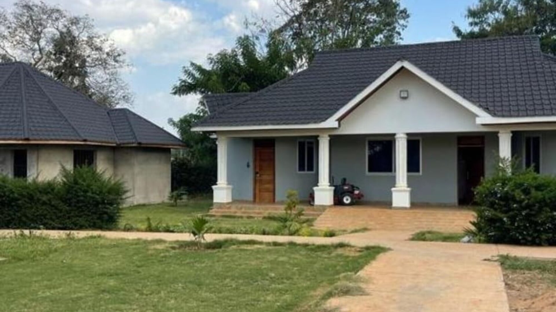 Exterior view of a private lodge unit surrounded by greenery, with a paved walkway and small porch area at Sega Lodge.