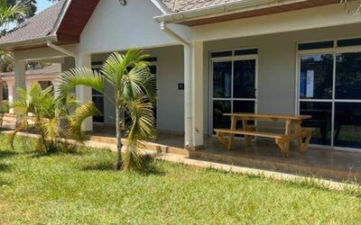Close-up exterior of a lodge building with tiled roof, covered patio, and outdoor seating area at Sega Lodge.