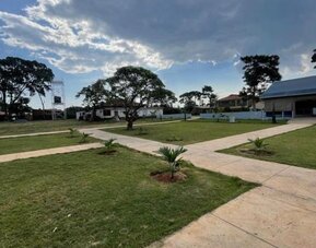 Open outdoor grounds with walking paths, greenery, and scattered lodge buildings under a partly cloudy sky at Sega Lodge.