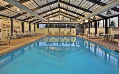 Indoor pool with lounge chairs, skylit ceiling, and large windows along the deck at Marriott SpringHill Suites Naperville/Warrenville.