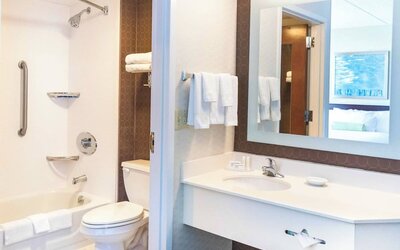 Bathroom at Marriott SpringHill Suites Naperville/Warrenville with tub shower combo, white vanity, and large mirror.