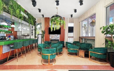 Modern lounge bar with green seating, pendant lights, marble feature wall, and indoor plants at Chesterfield Hotel & Suites.