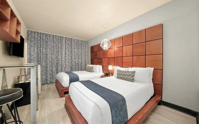 Double bed room with wood headboards, gray runners, workspace, and floor-length curtains at Chesterfield Hotel & Suites.
