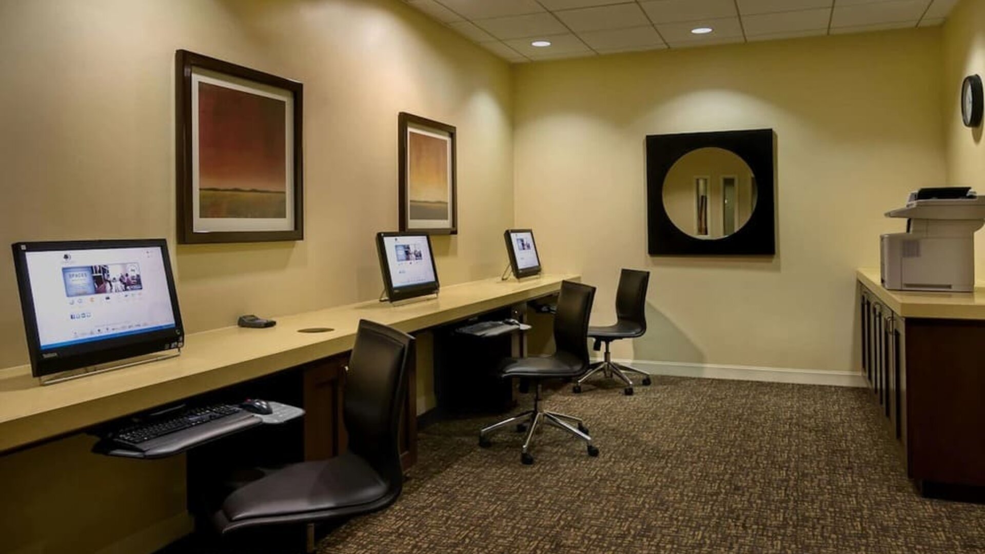 Business center with desktop computers, swivel chairs, long work counter, and printer station at DoubleTree By Hilton Los Angeles Downtown.