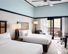 Guest room with two beds, work desk, balcony access, and neutral-toned decor at The Ambrose Hotel Santa Monica.