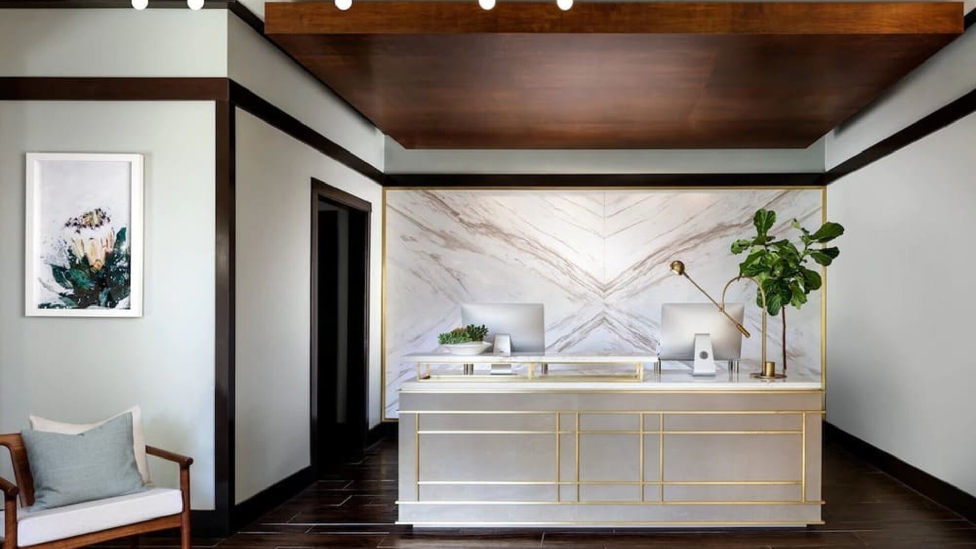 Reception desk with marble backdrop, wood accents, and minimalist decor in a modern lobby setting at The Ambrose Hotel Santa Monica.