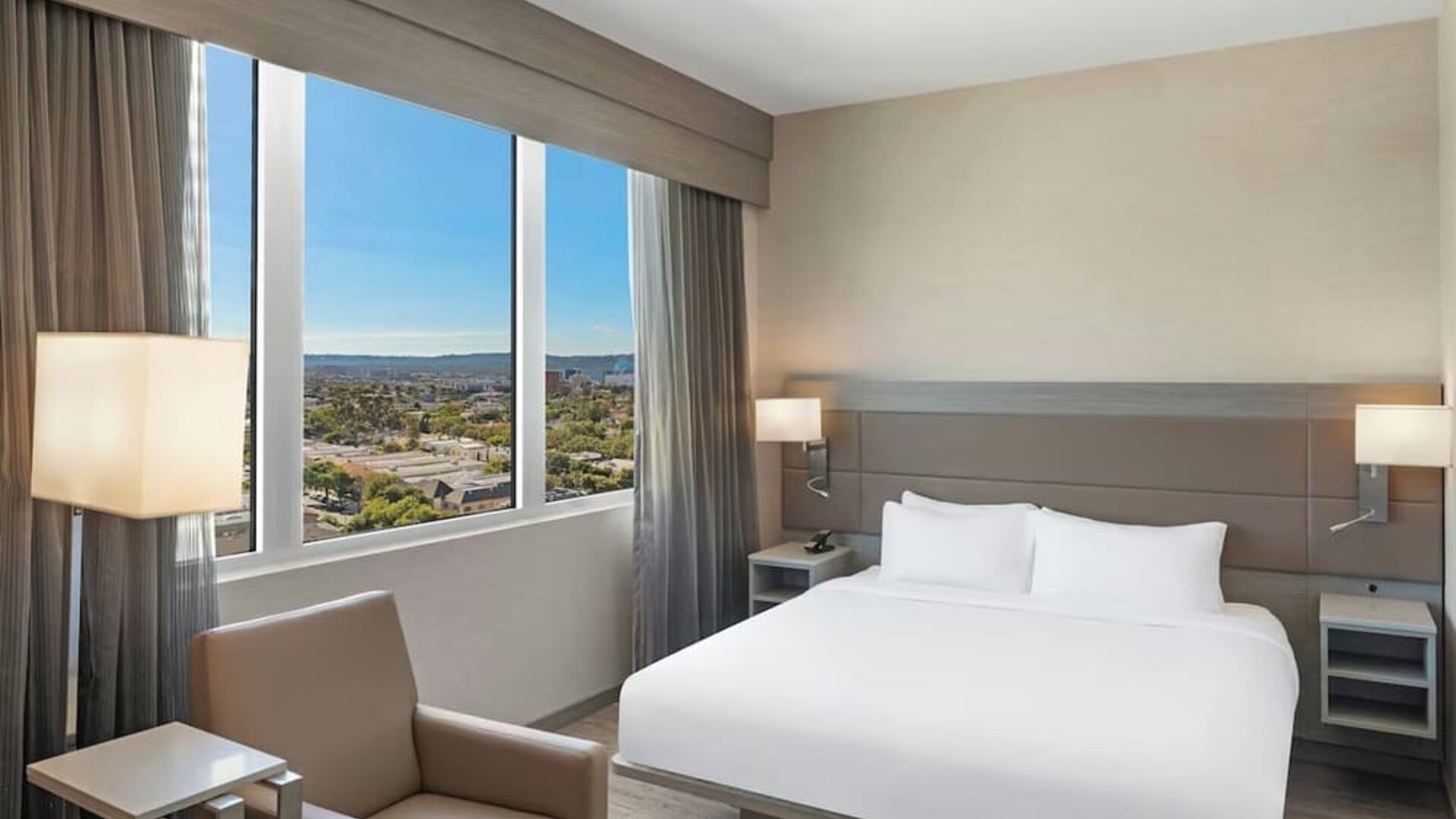 Guest room with king bed, large window view, bedside lighting, and minimal modern decor at AC Hotel By Marriott Beverly Hills.