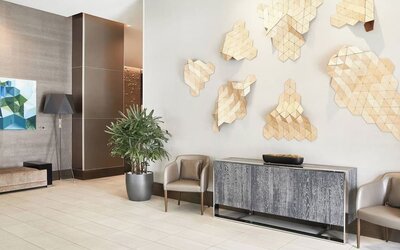 Lobby seating area with geometric wall art, potted plants, and contemporary furniture at AC Hotel By Marriott Beverly Hills.
