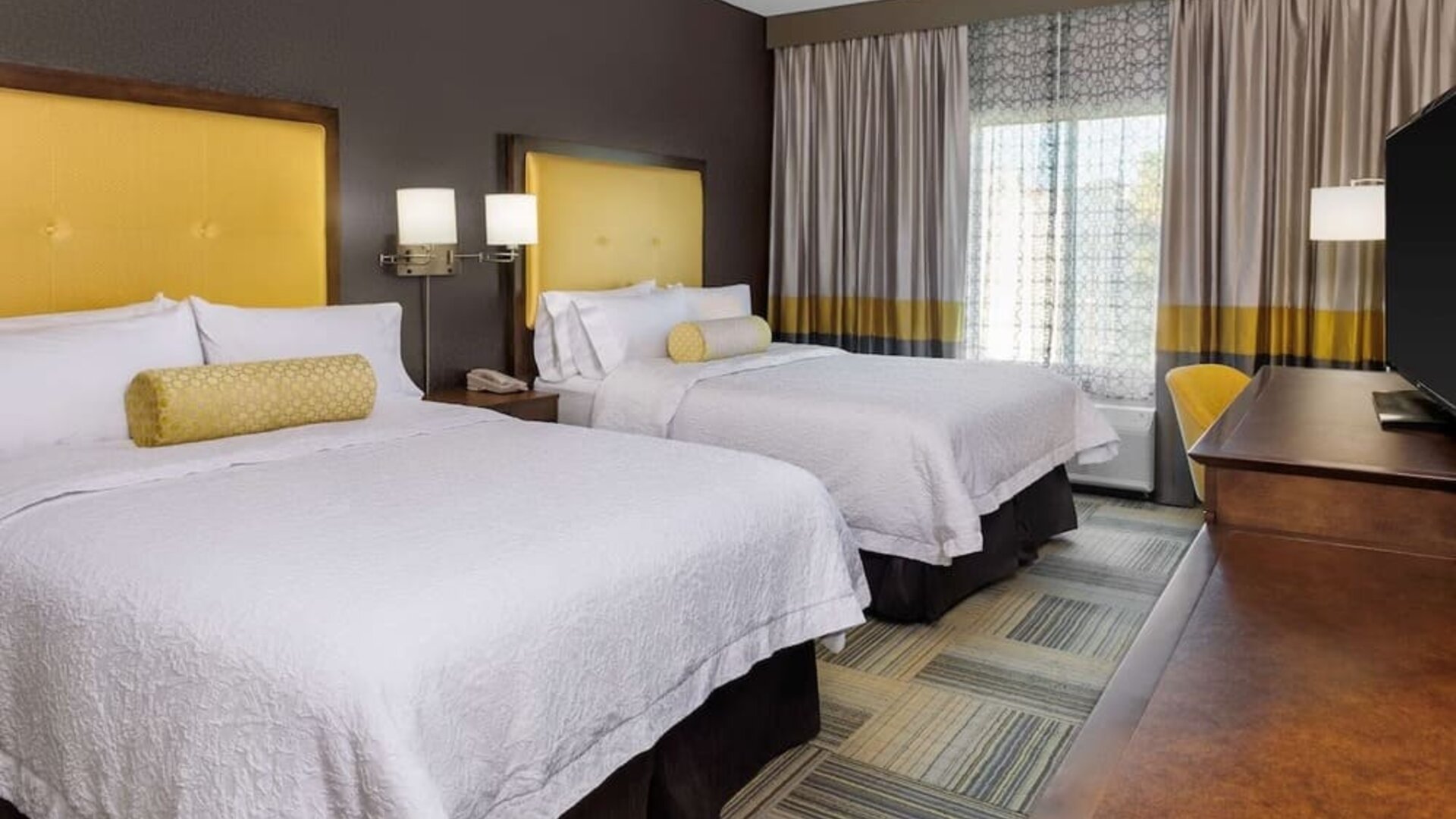 Guest room with two beds, yellow headboards, window seating, and coordinated décor at Hampton Inn & Suites Los Angeles / Hollywood.