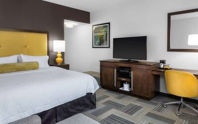 Guest room with king bed, yellow upholstered headboard, work desk, TV, and modern furnishings at Hampton Inn & Suites Los Angeles / Hollywood.