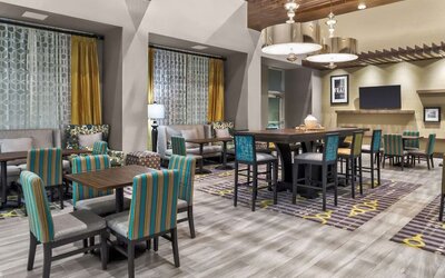 Dining/lounge area with patterned chairs, communal tables, warm lighting, and contemporary décor at Hampton Inn & Suites Los Angeles / Hollywood.