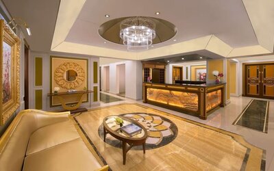 Reception area with curved desk, chandelier ceiling feature, and gold-accented décor