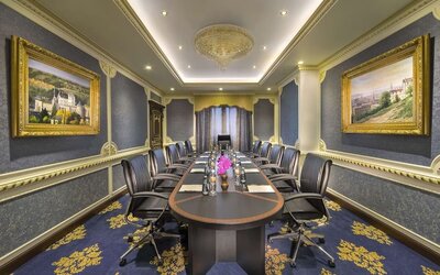 Long conference room with central table, leather chairs, chandeliers, and framed artwork