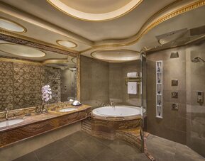 Large marble bathroom with soaking tub, glass shower, dual sinks, and decorative ceiling panels