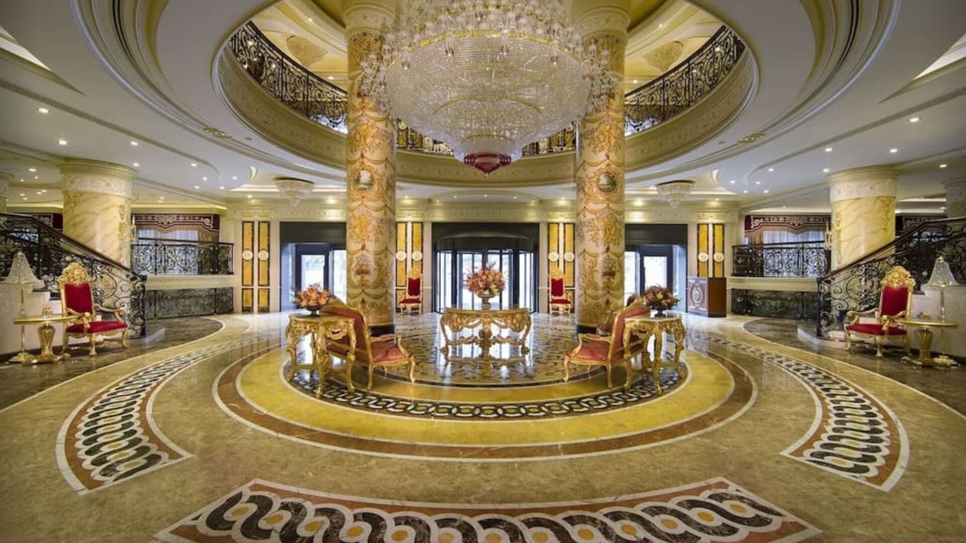 Grand lobby with circular layout, chandeliers, marble floors, and central seating arrangement