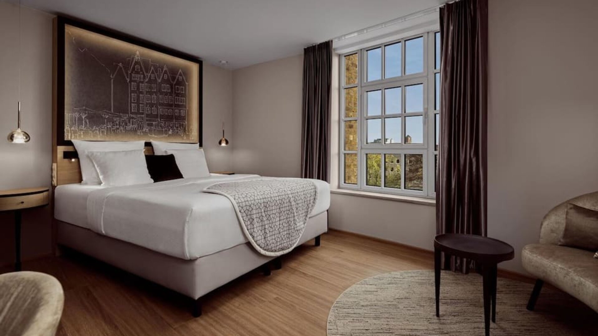 King room with lit headboard art, round rug, side table, and soft neutral tones throughout