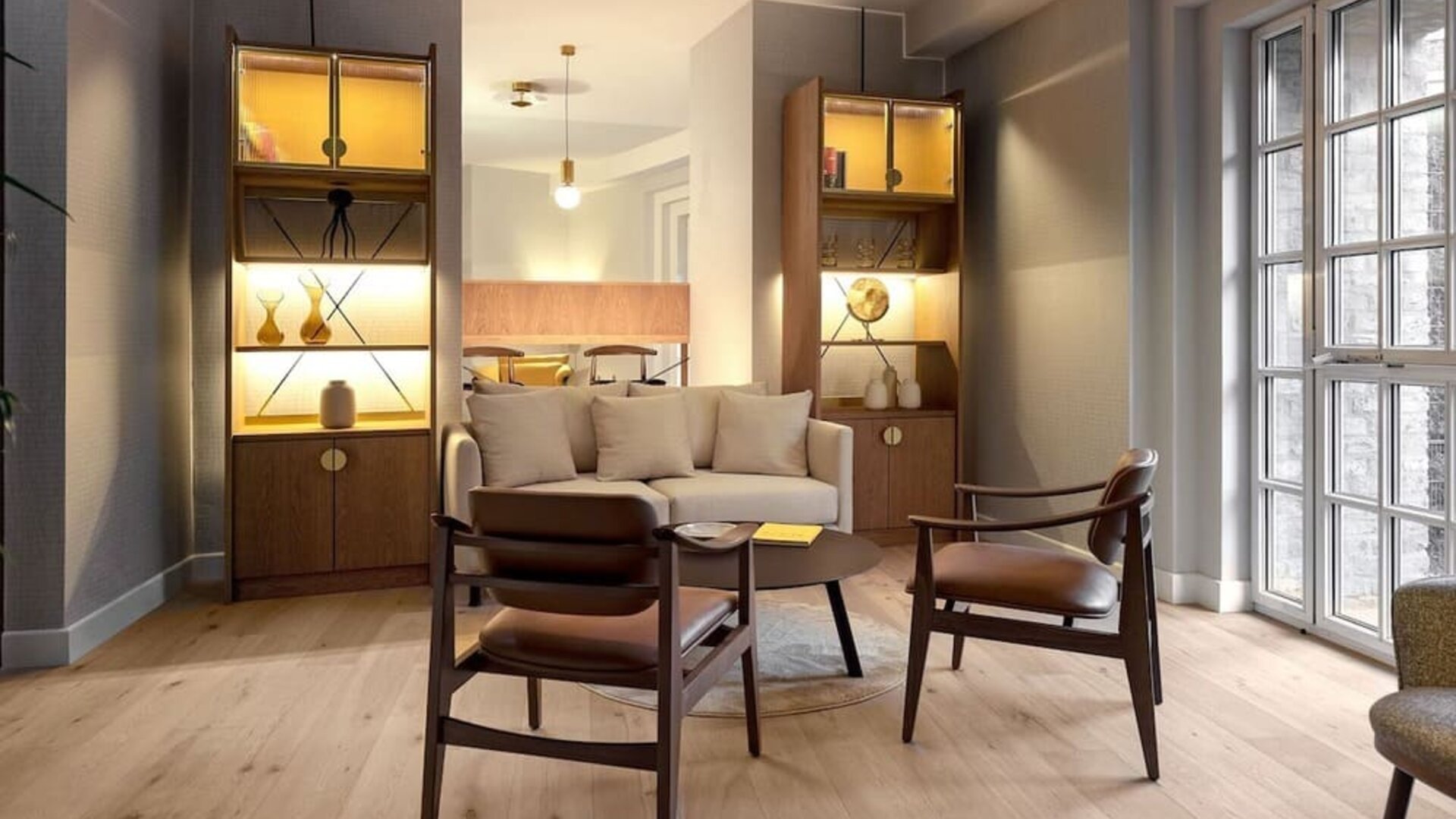 Lounge area with sofa, armchairs, coffee table, and built-in shelves with warm accent lighting
