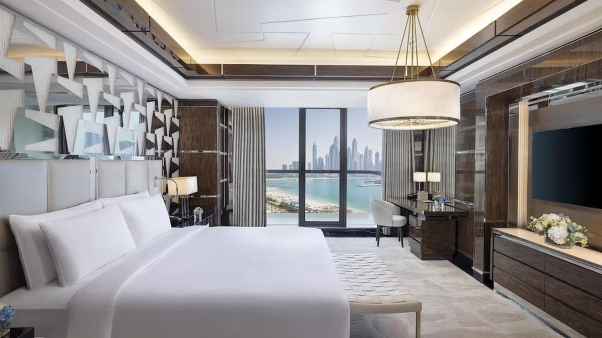 King bedroom with large bed, decorative headboard, desk area, and balcony with marina skyline view