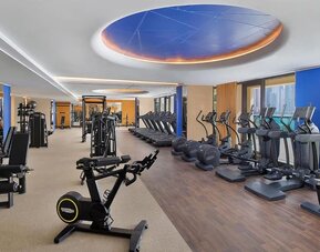 Spacious fitness center with cardio machines, weight equipment, and large windows facing the water
