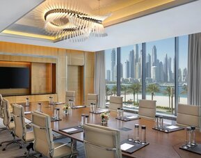 Conference room with long table, leather chairs, and large windows overlooking waterfront skyline