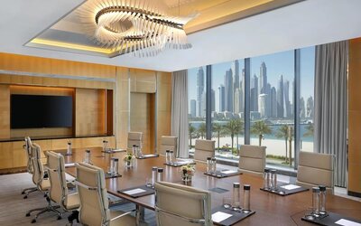 Conference room with long table, leather chairs, and large windows overlooking waterfront skyline