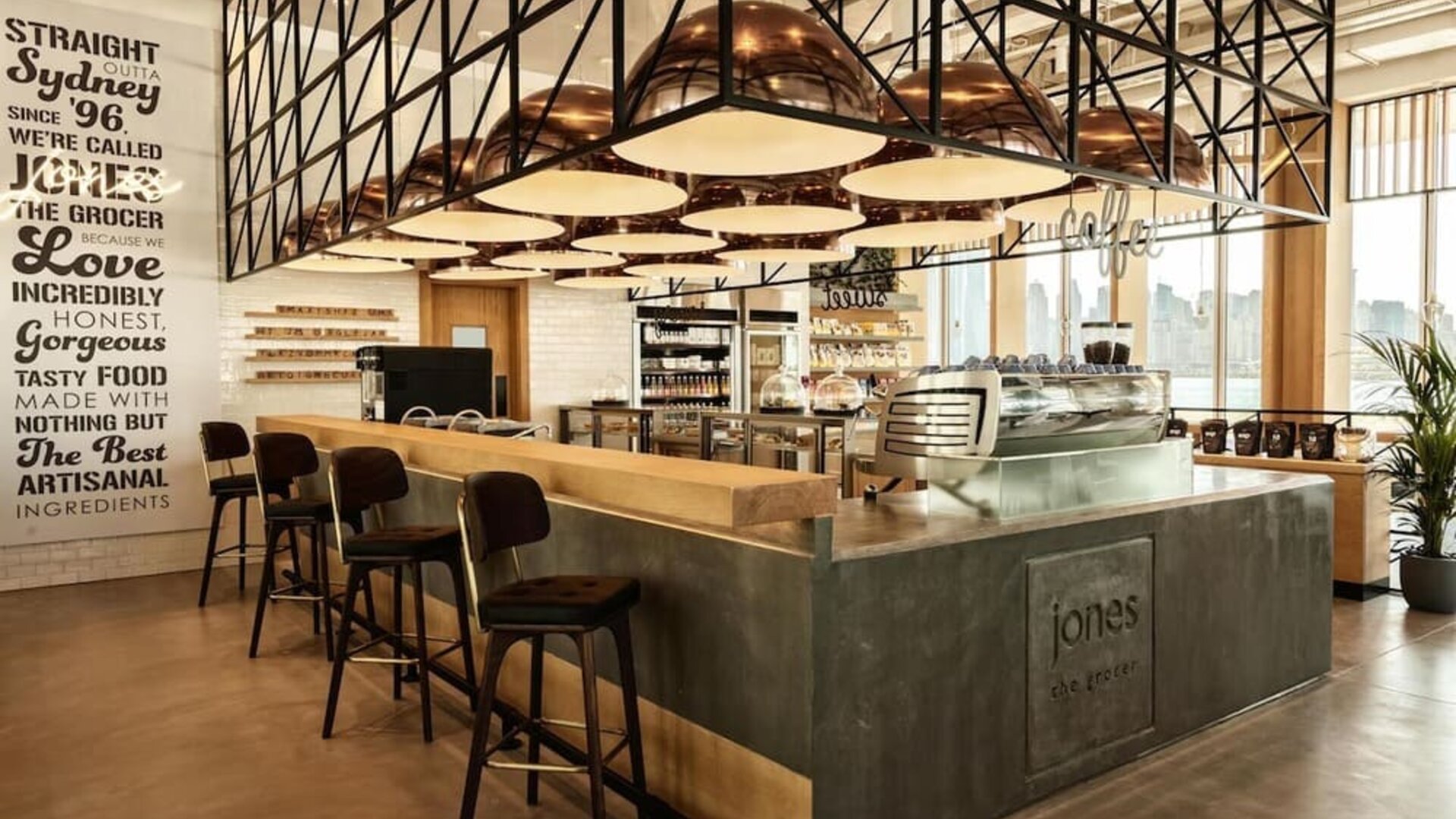 Stylish café bar with high stools, espresso machine, pendant lighting, and warm wood and metal finishes