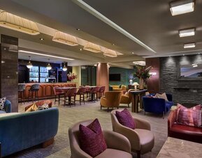 Lounge with colorful armchairs, bar seating, and warm lighting creating a relaxed social atmosphere